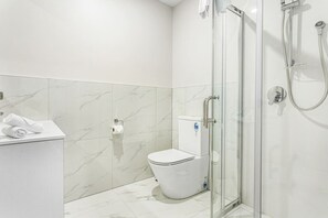 Une salle de bain moderne avec une douche à parois de verre, des toilettes blanches et un sol carrelé en marbre.