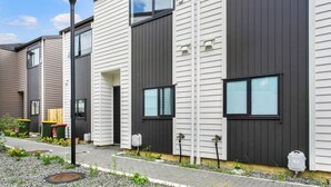 A modern residential building with a symmetrical facade, large windows, and a pathway leading to the entrance. - Urban Pulse Townhouse with parking (Auckland South)