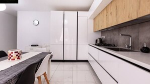 Une cuisine moderne avec des meubles blancs, un plan de travail en bois et un coin repas comprenant une table et des chaises.