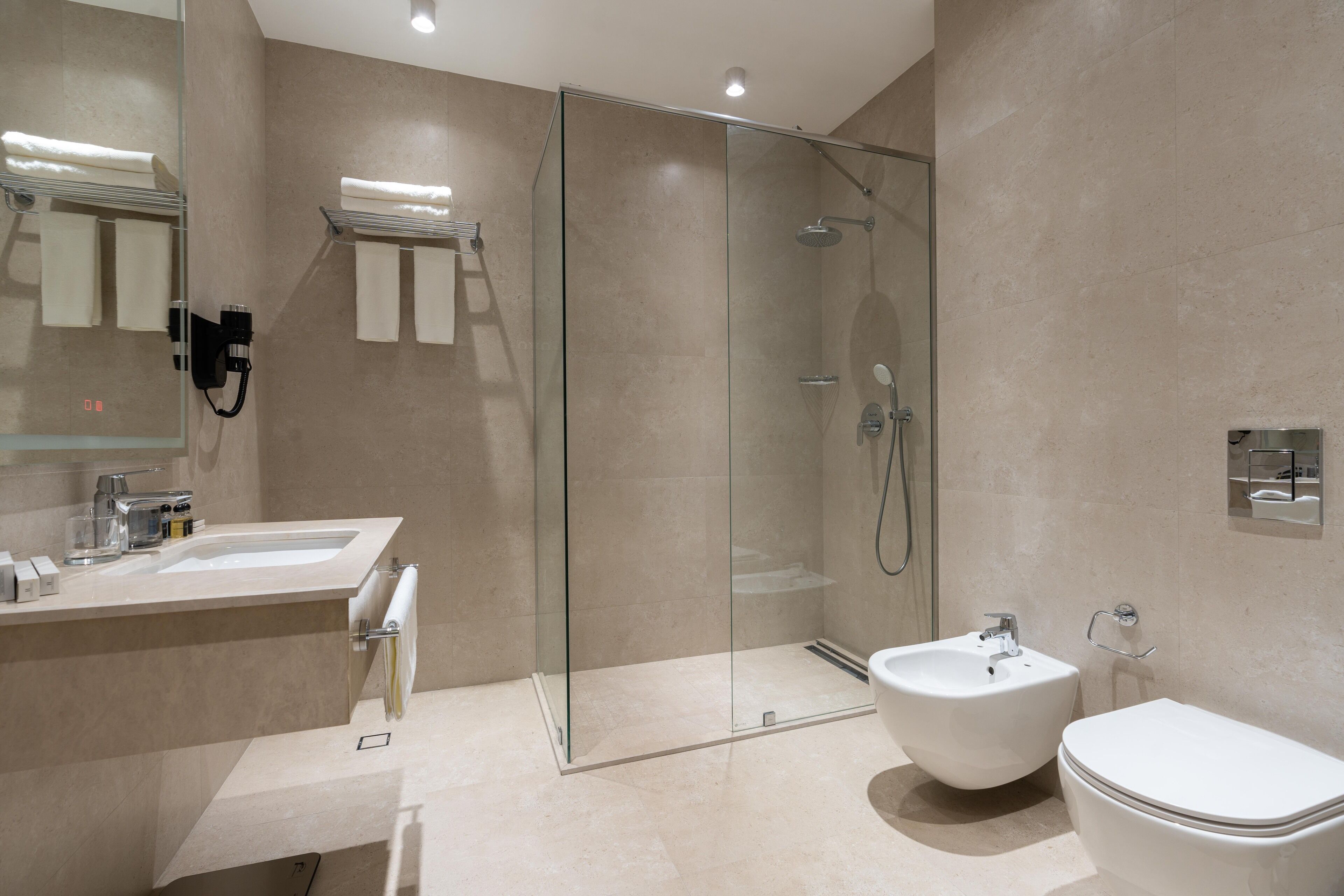 Ein modernes Badezimmer mit einer Glaskabine zur Dusche, einem Waschbecken und einer Toilette.