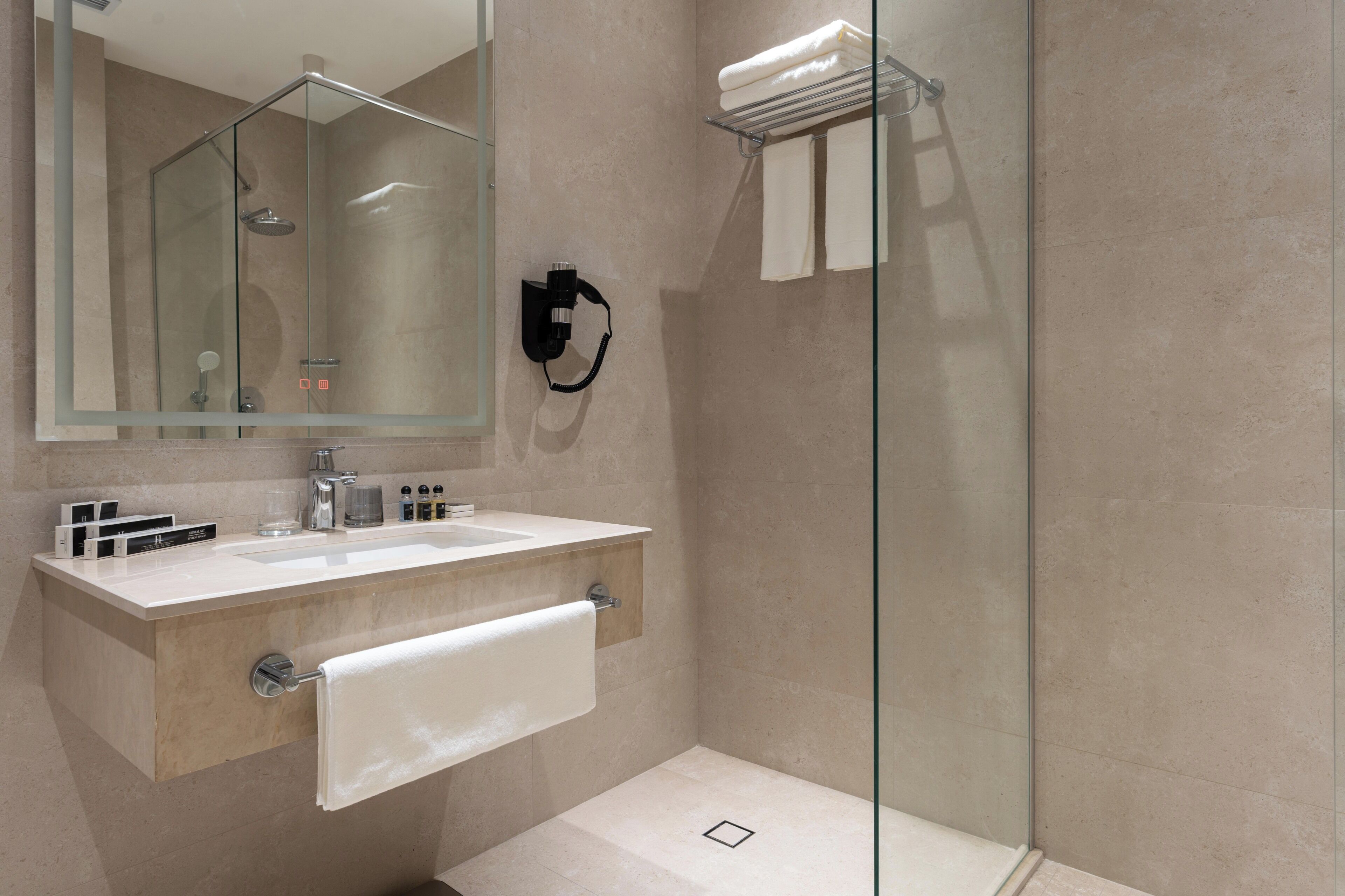 A modern bathroom with a glass shower enclosure, a vanity with a mirror, and a towel rack.