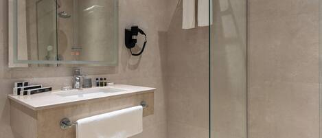 A modern bathroom with a glass shower enclosure, a vanity with a mirror, and a towel rack.