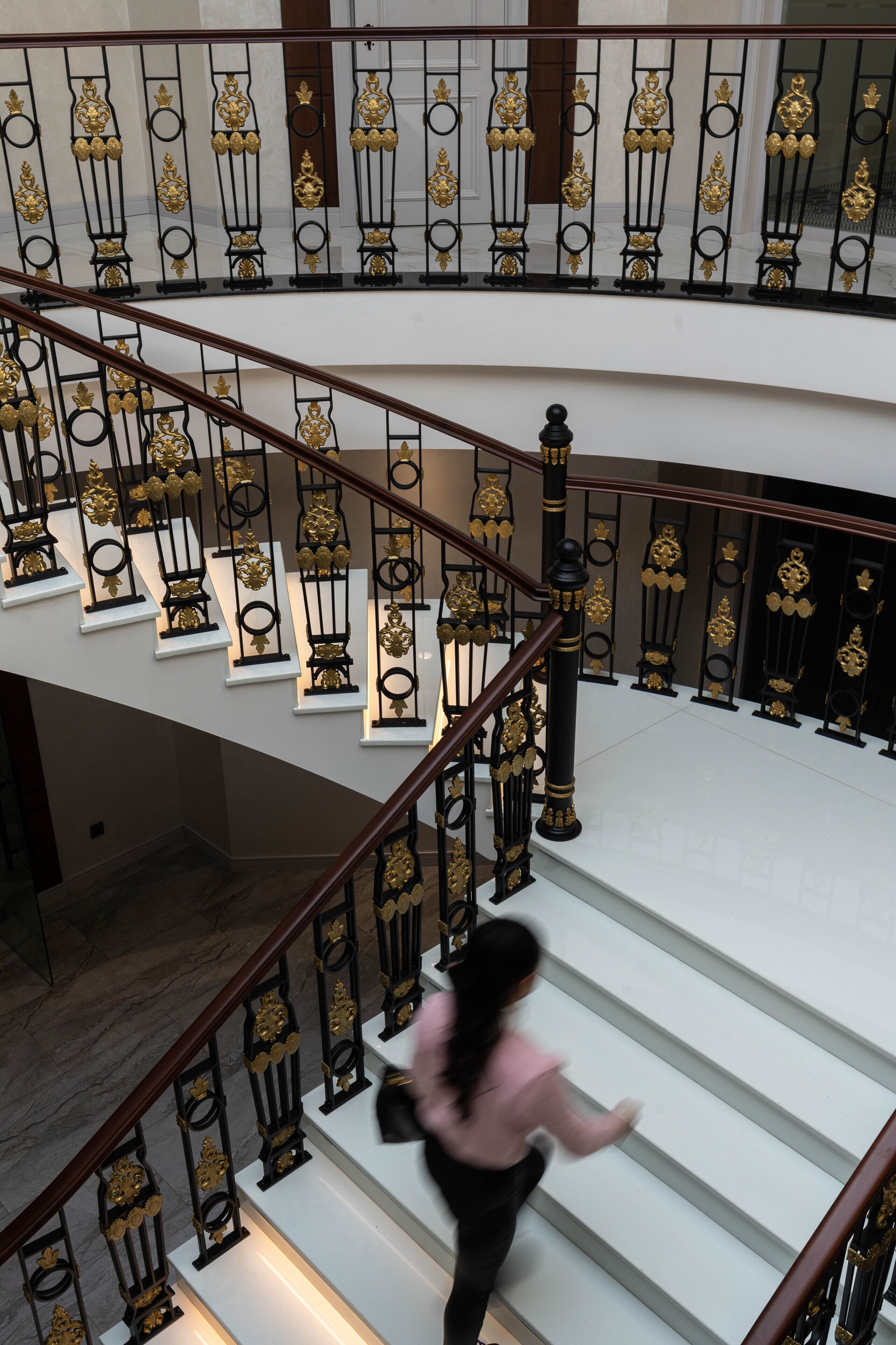 A multi-level staircase with ornate black and gold railings and white steps.