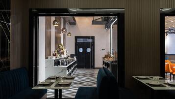 Un comedor moderno con un patrón geométrico en el suelo, asientos azul oscuro y una barra con encimera de mármol blanco.