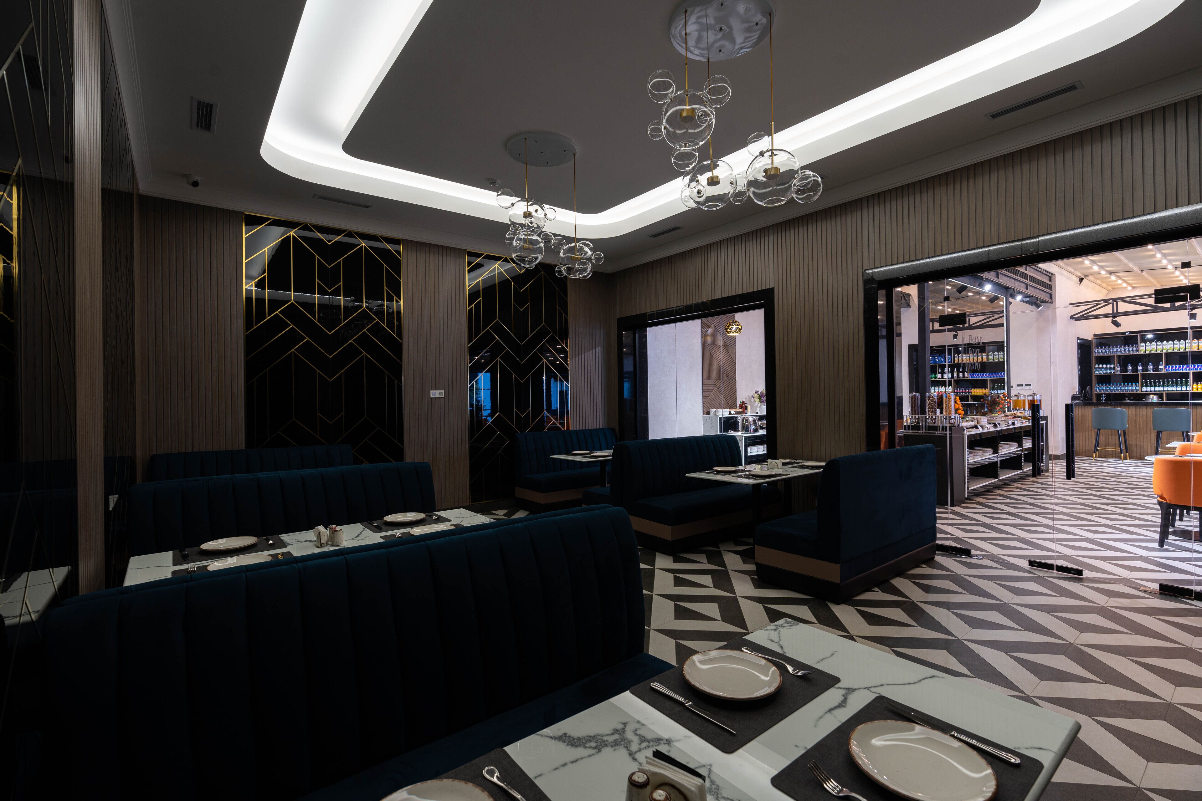 Ein modernes Restaurant mit dunkelblauen Sitzecken und einem geometrisch gemusterten Boden.