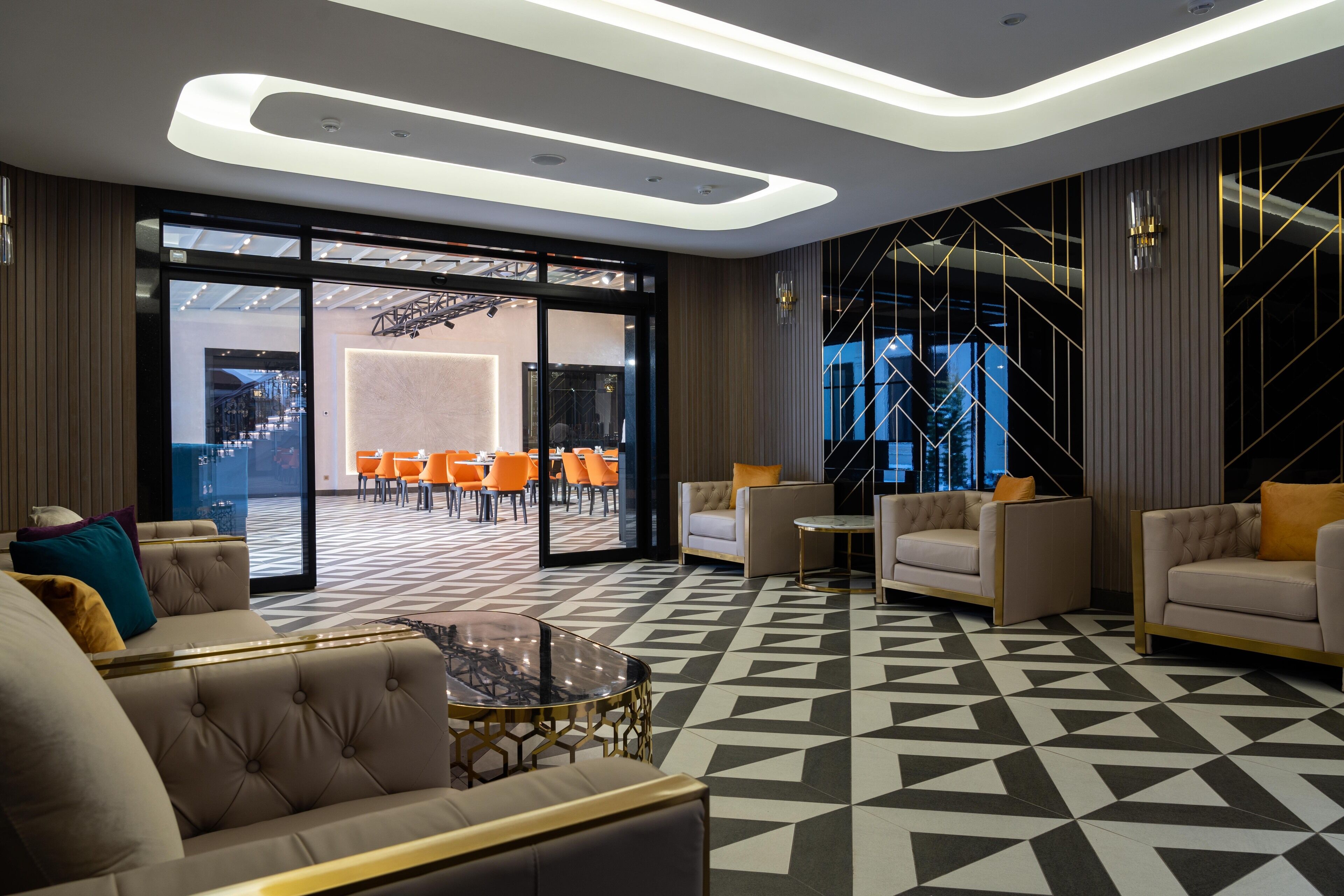 A modern lobby with a geometric patterned floor, leather sofas, and a glass coffee table.