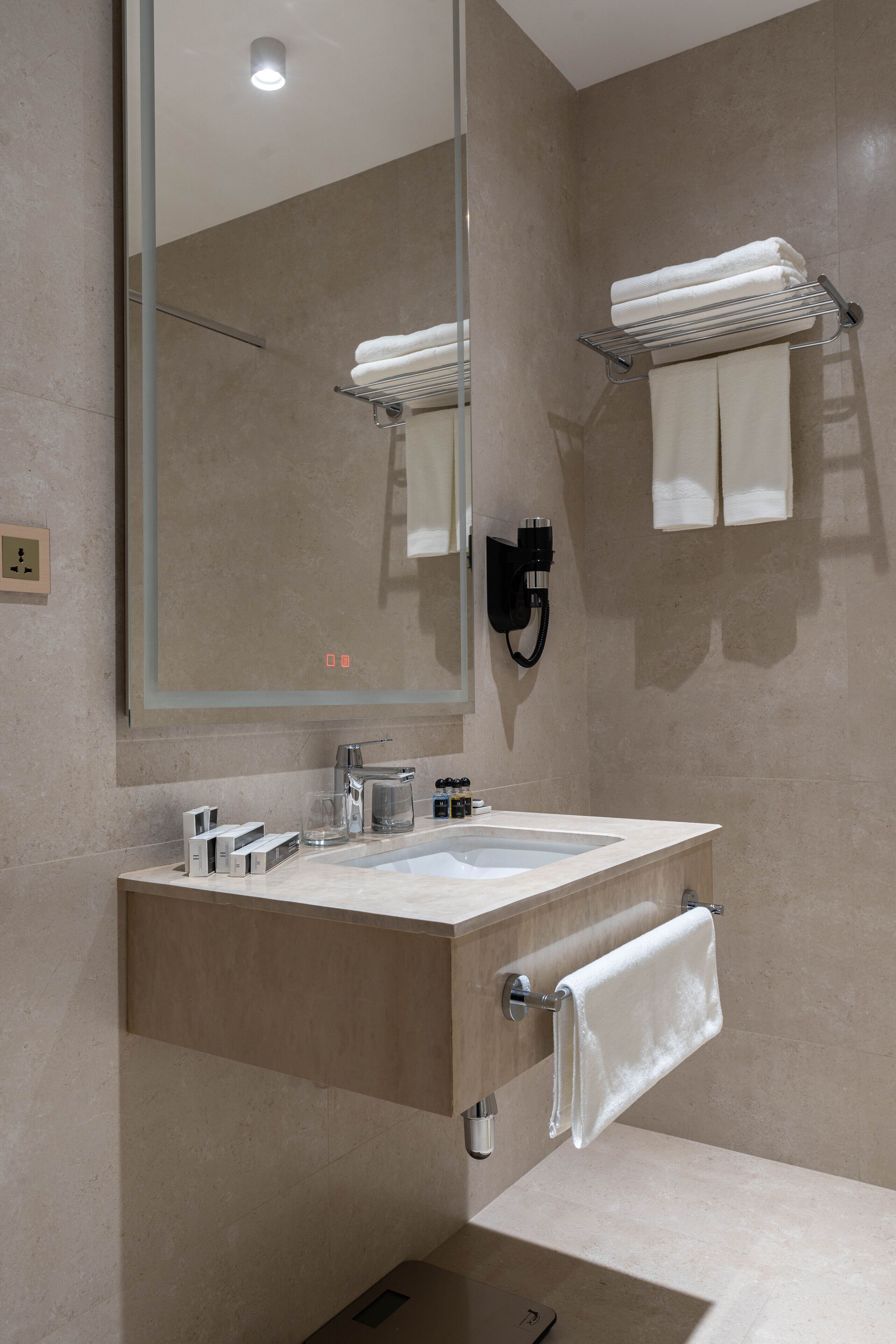 A modern bathroom with a large mirror, a sink, a towel rack, and a towel hanging on the wall.