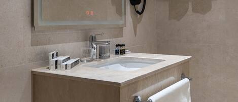 A modern bathroom with a large mirror, a sink, a towel rack, and a towel hanging on the wall.