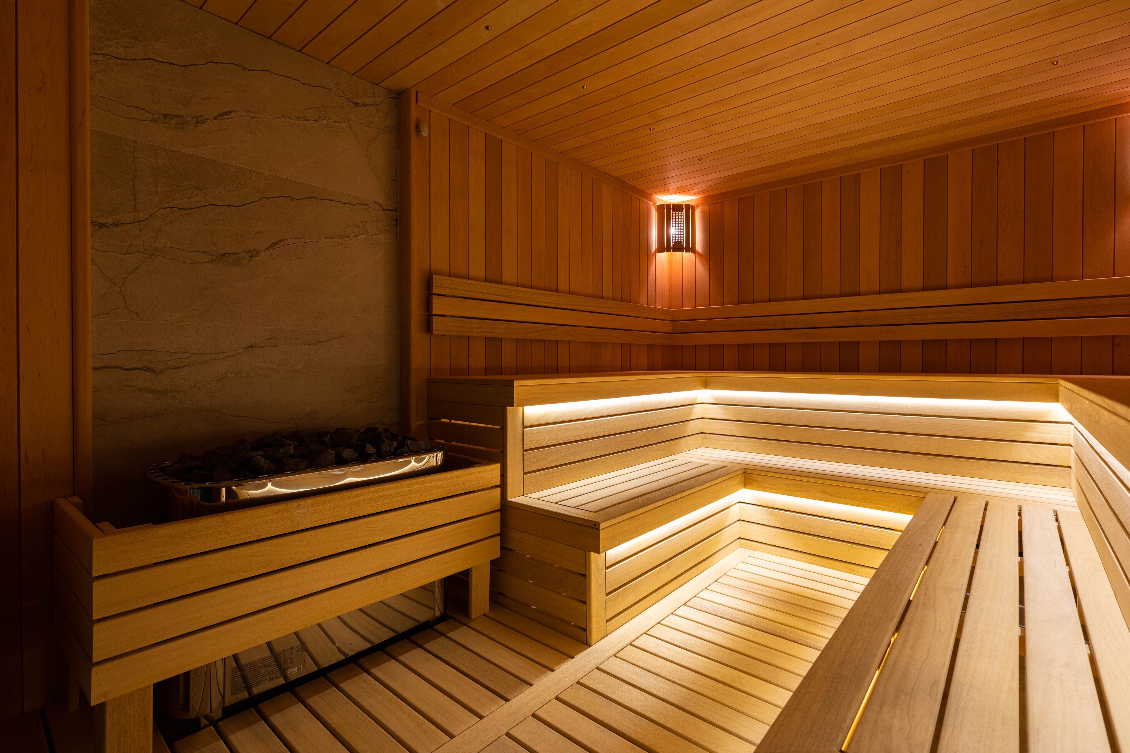 Een sauna met houten banken en een stenen muur.