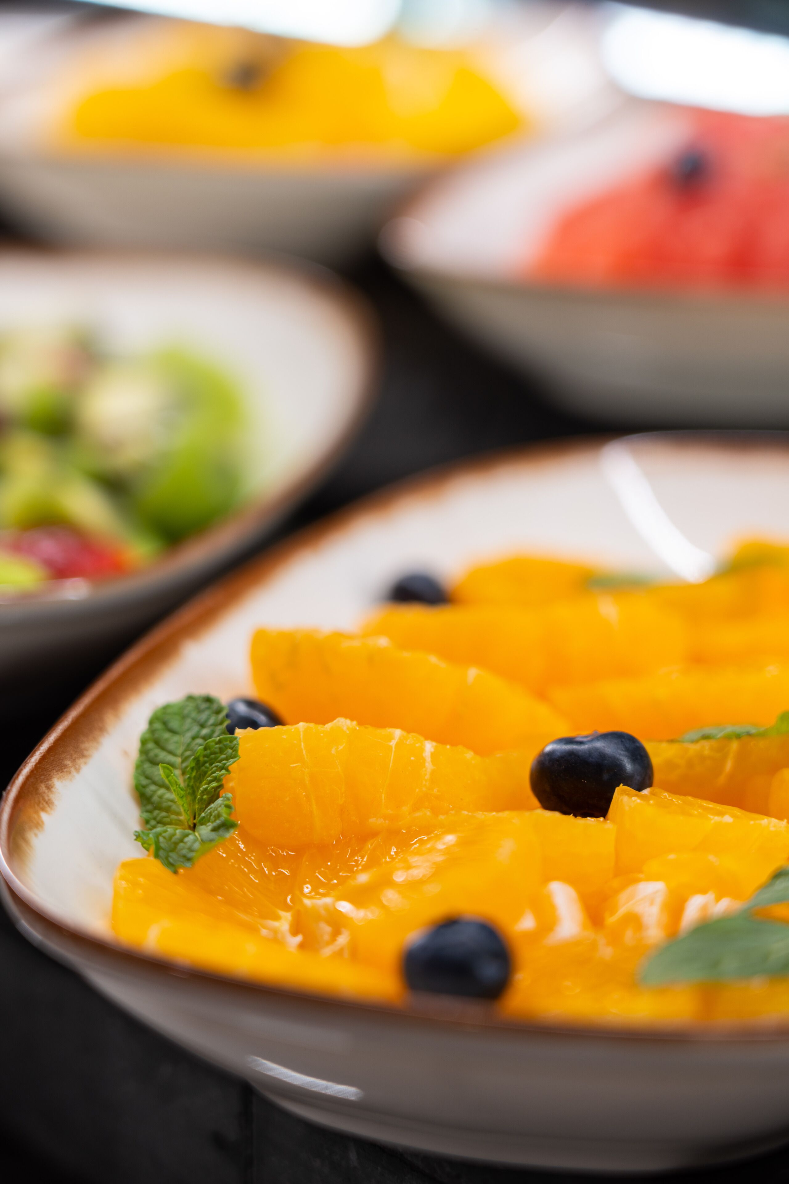 A close-up of a fruit salad with orange segments, blueberries, and mint leaves.