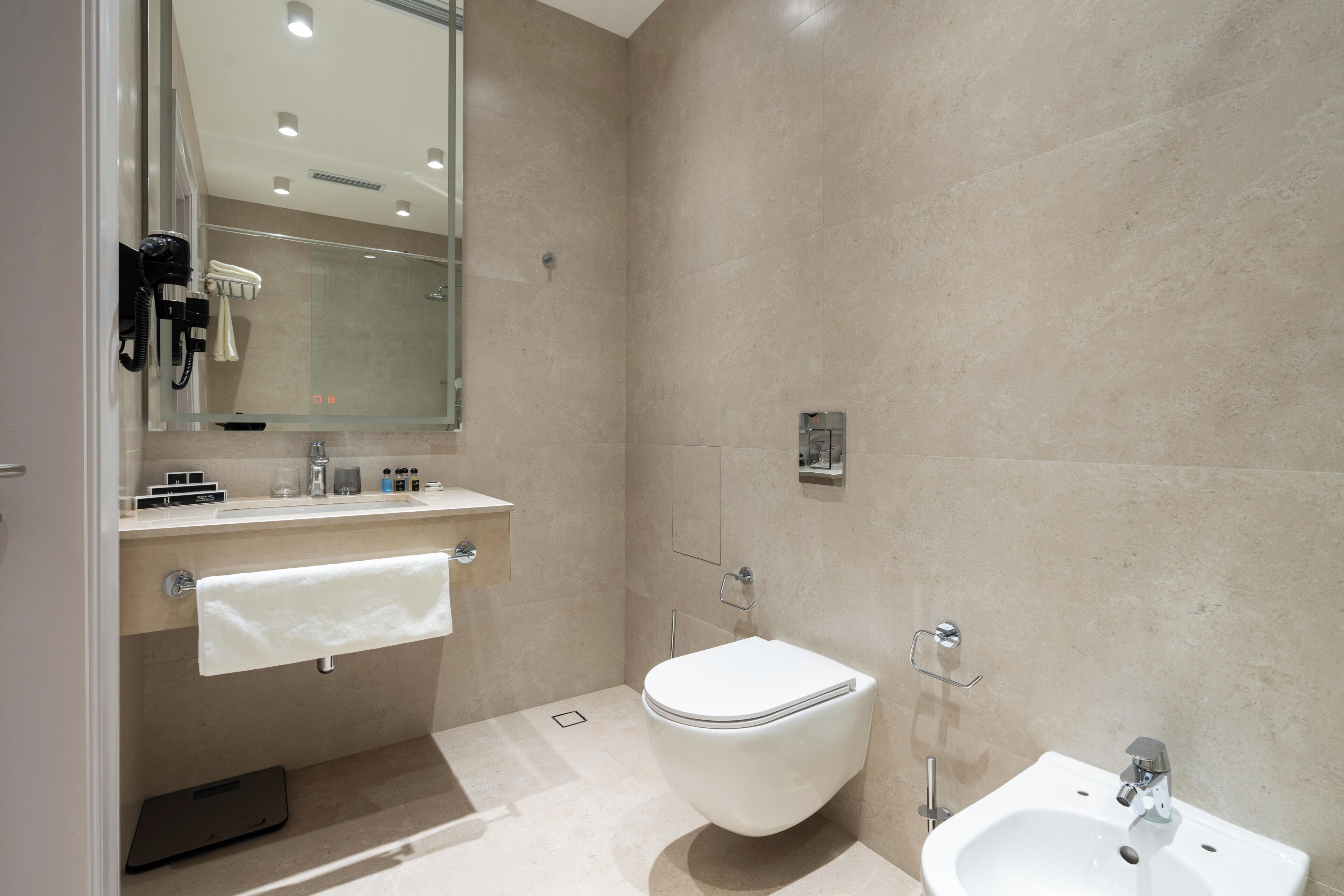 A modern bathroom with a toilet, sink, and towel rack.