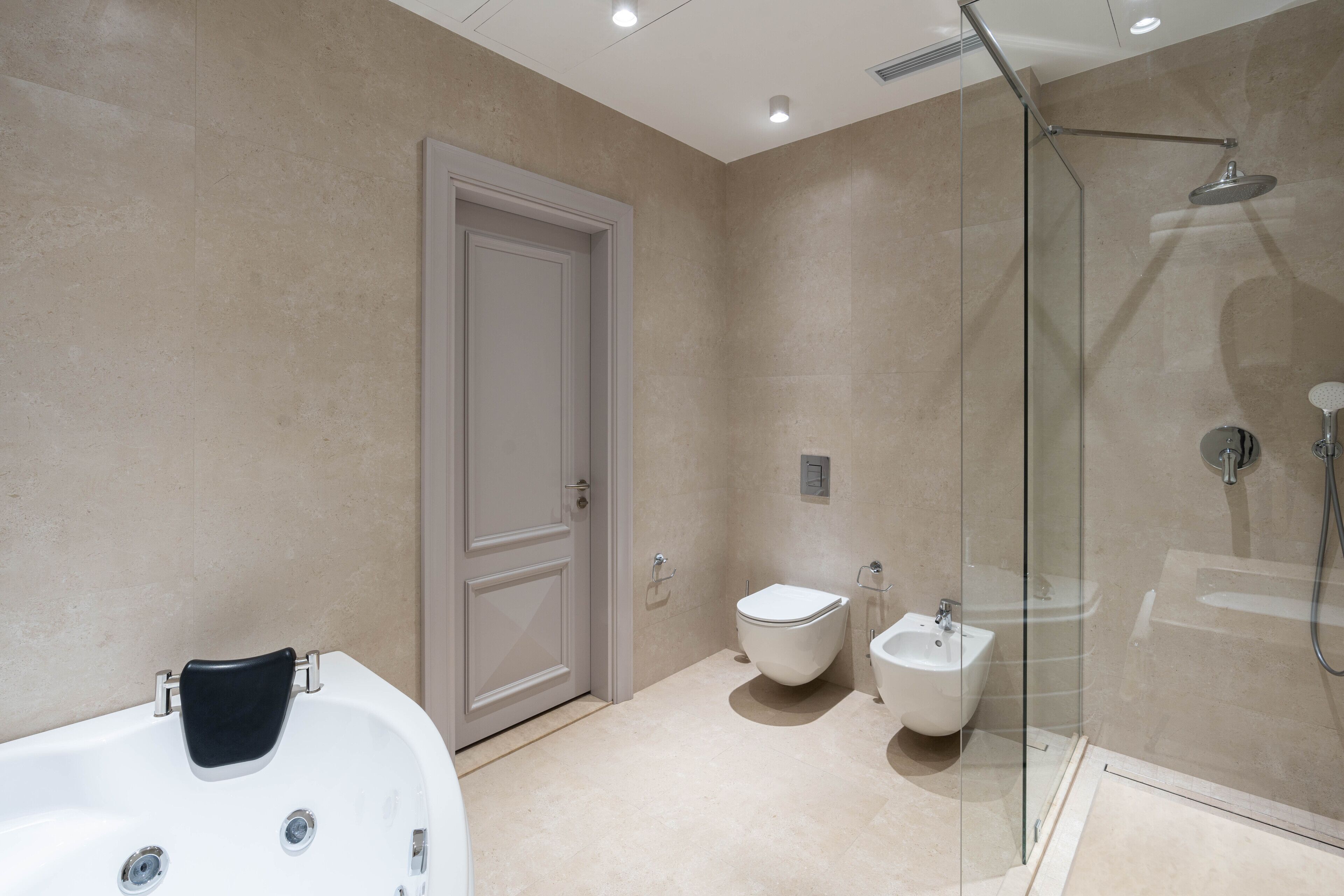 A modern bathroom with a glass-enclosed shower, a white bathtub, and a bidet.