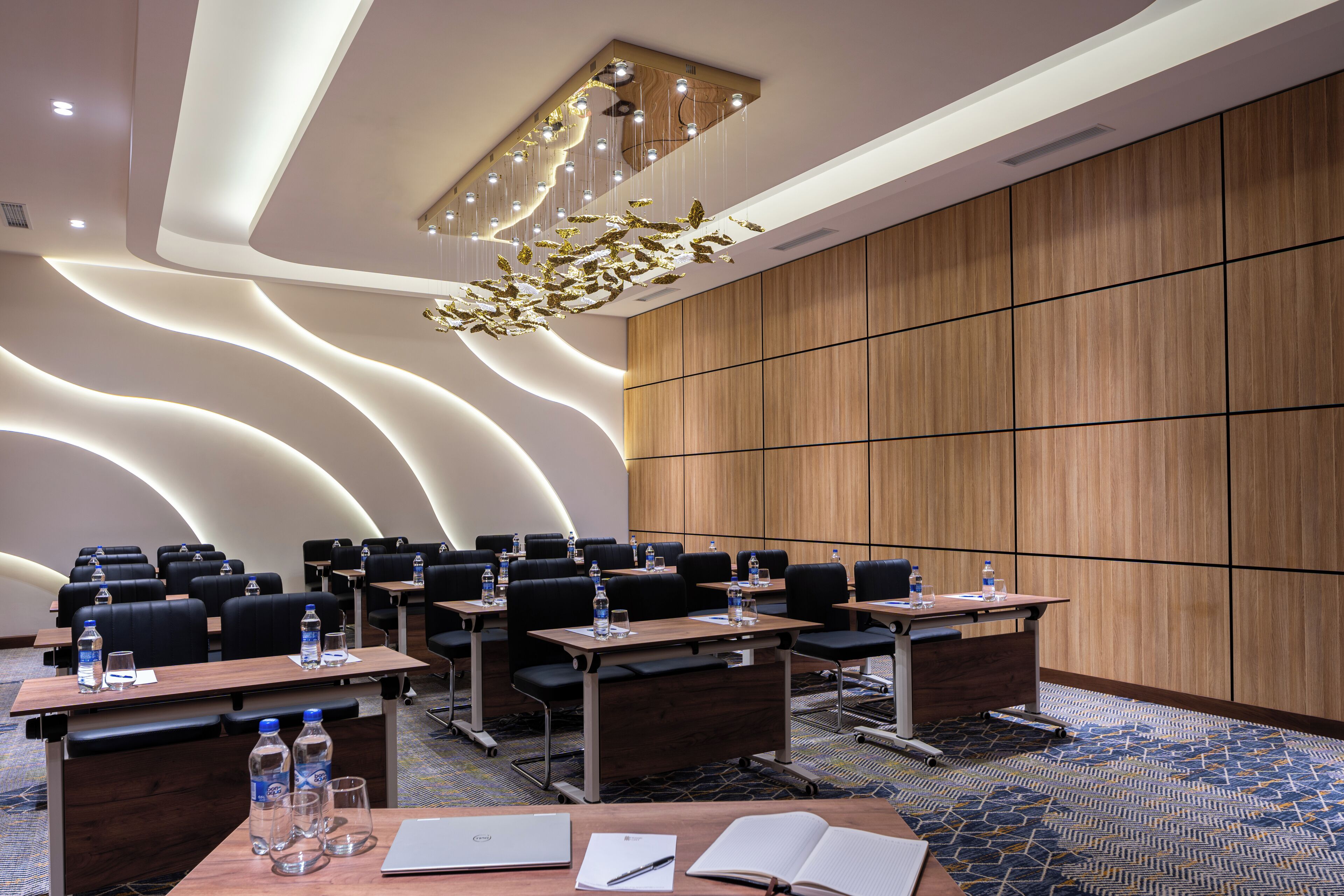 A conference room with multiple tables, chairs, and a large wooden panel wall.