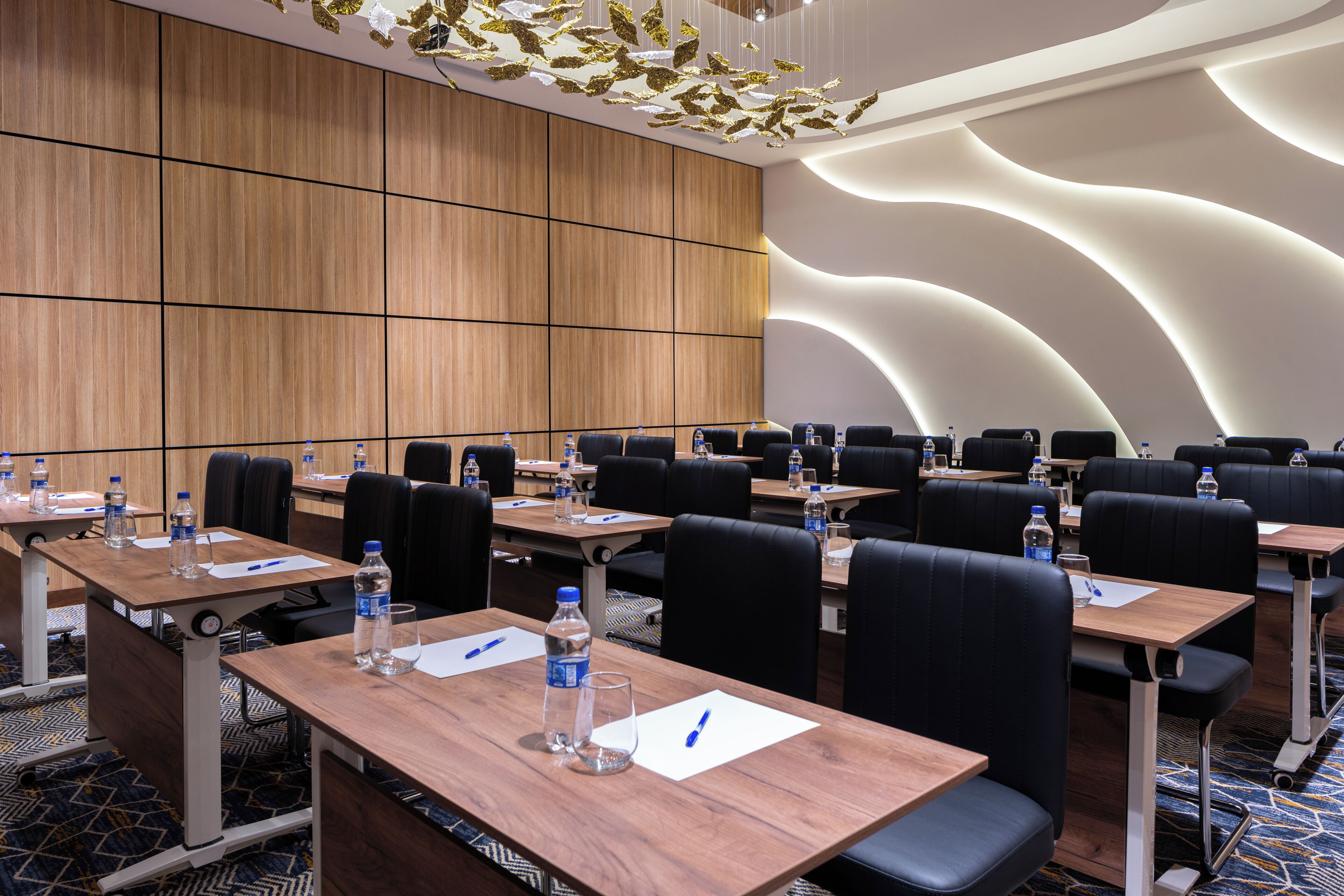A conference room with multiple tables, chairs, and water bottles.