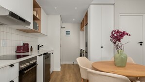 A modern kitchen with white cabinets, a wooden countertop, and a dining area with a table and chairs.