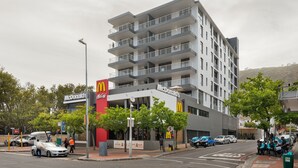 A multi-story building with a McDonald's restaurant on the ground floor, featuring balconies and a modern architectural design.