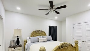 A bedroom with a wooden bed, a nightstand with a lamp, a ceiling fan, and a wardrobe. - New & Modern 2b/2b Apartment 
Centrally located   (Pharr)
