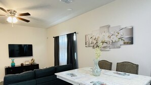 A dining area with a table, bench, and chairs. There is a sofa and a TV in the background. - New & Modern 2b/2b Apartment 
Centrally located   (Pharr)