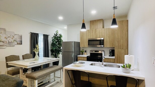 A modern kitchen with a central island, wooden cabinets, and stainless steel appliances. - New & Modern 2b/2b Apartment 
Centrally located   (Pharr)