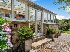 A cottage with a glass front, stone steps, and potted plants.