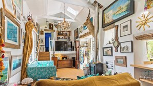 A cozy, well-decorated living room with a fireplace, comfortable seating, and various wall decorations.