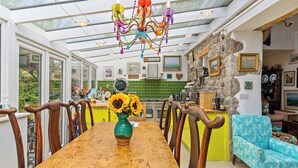 A dining area with a wooden table, chairs, and a vase of sunflowers.