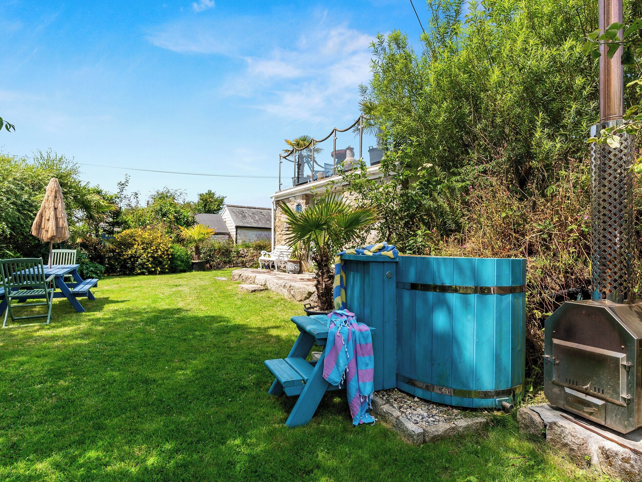 Een achtertuin met een barbecue, een picknicktafel en een overdekte zithoek.