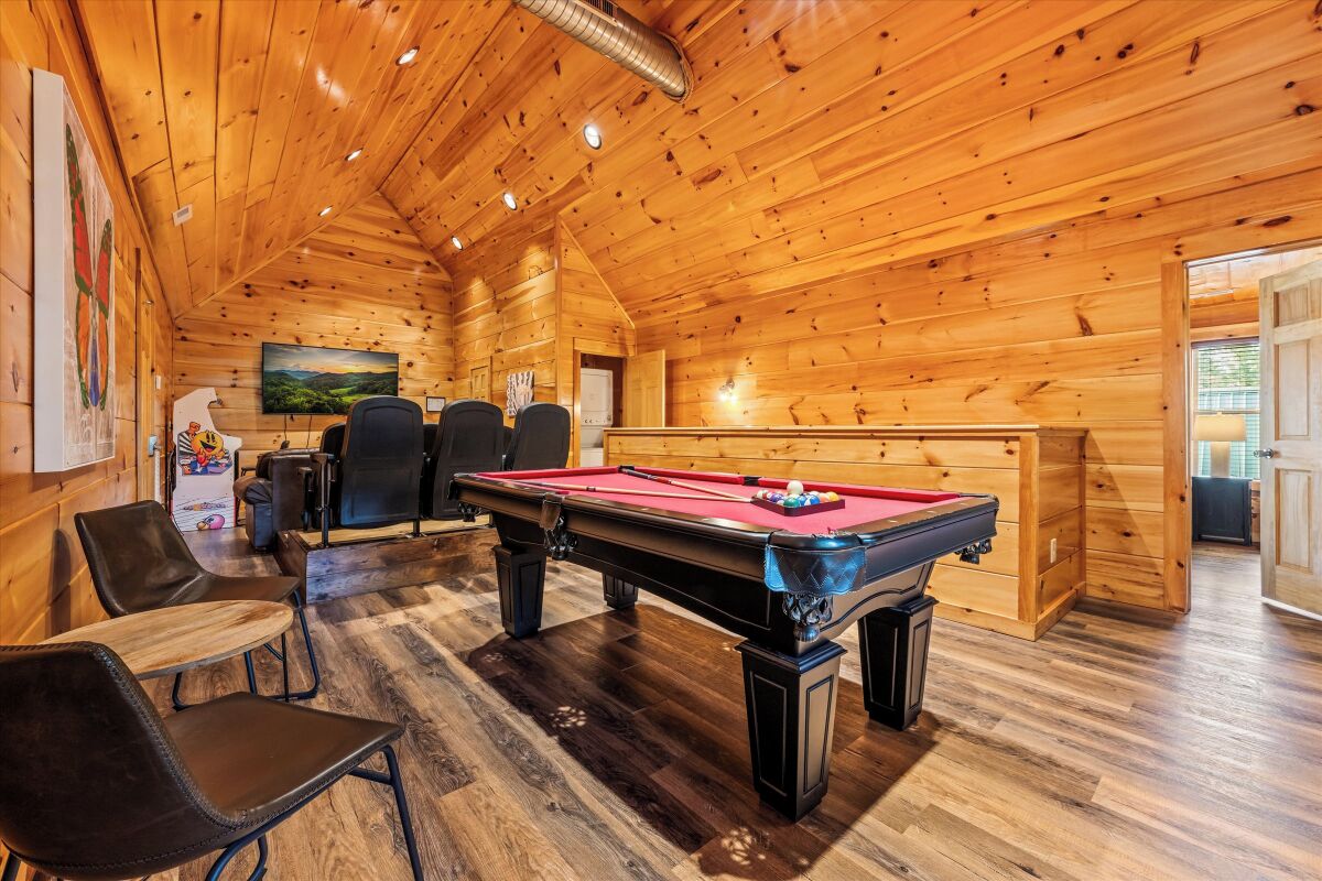 A wooden interior with a pool table, seating area, and a painting on the wall.