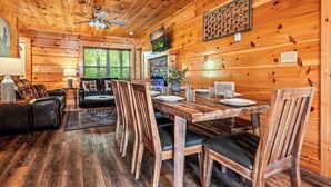 A wooden interior with a dining table set for four, surrounded by wooden chairs.