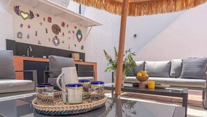Un espace de vie extérieur moderne comprenant un canapé, une table basse avec des pots et un mur décoratif.