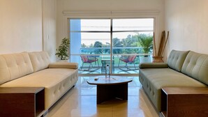 A modern living room with two sofas facing a glass door leading to a balcony with outdoor furniture. - Minarete By Wynwood House  (Cartagena)