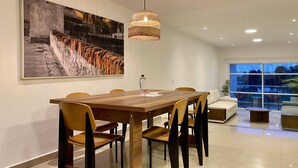 A modern dining area with a wooden table and chairs, a large painting on the wall, and a hanging light fixture. - Minarete By Wynwood House  (Cartagena)