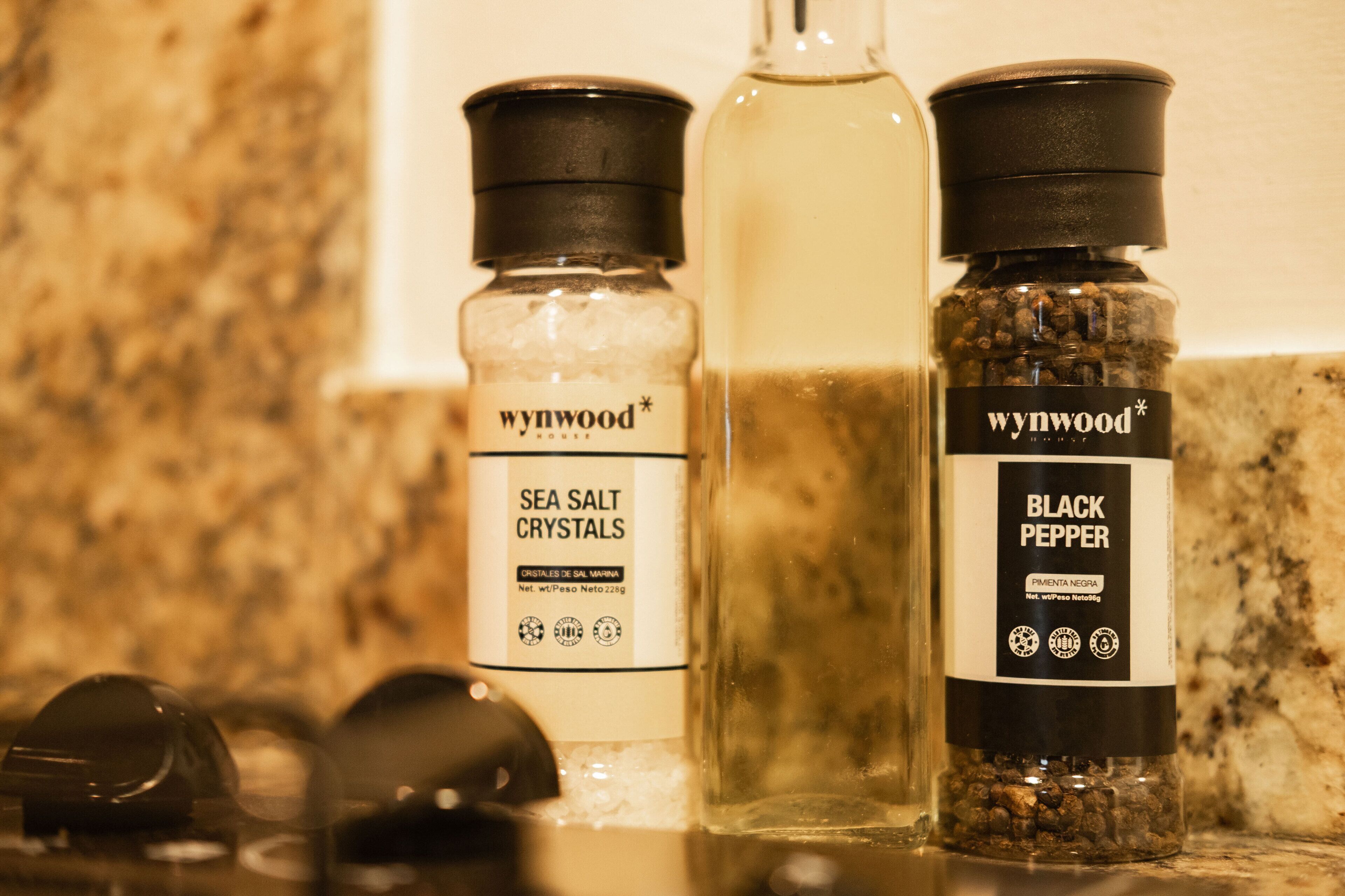 Tres botellas de Cristales de Sal Marina y Pimienta Negra Wynwood House sobre una encimera de cocina.