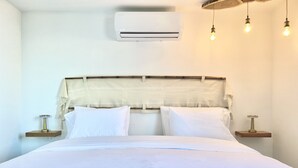A neatly made bed with white linens, a wooden headboard, and bedside tables with lamps. - Minarete By Wynwood House  (Cartagena)