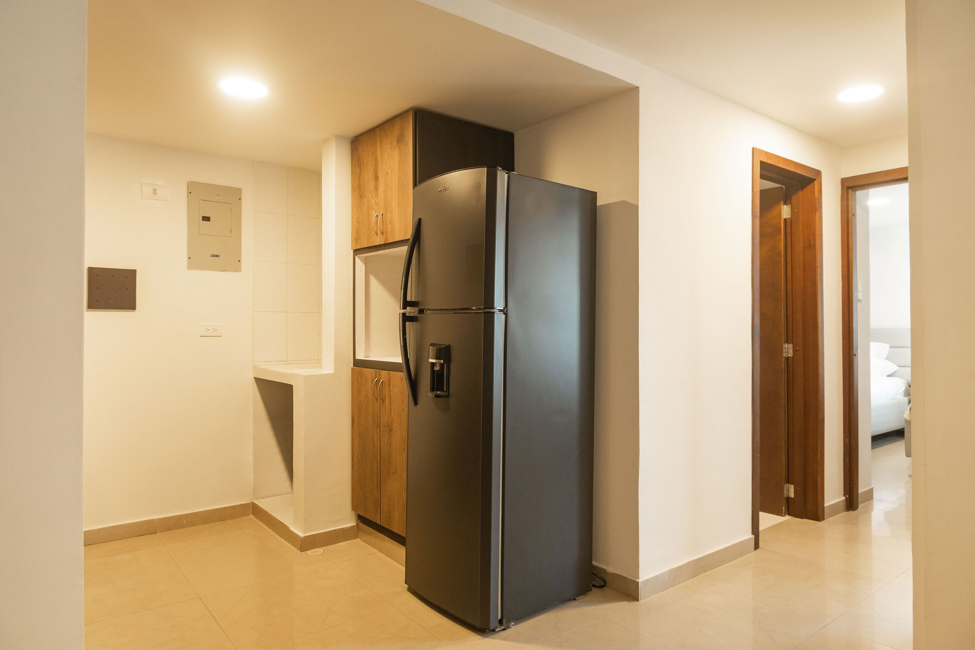 Una cucina moderna con frigorifero integrato, mobili in legno e pavimento piastrellato.