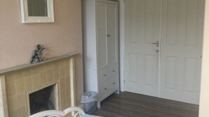 A room with a fireplace, a white wardrobe, and a closed door. - TDM Bachelot Lettings Ltd (London)