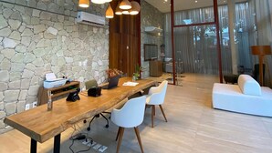 A modern dining area with a long wooden table, white chairs, and pendant lighting. - Flat Ilê de Pipa Sky - By Almare (Tibau do Sul)