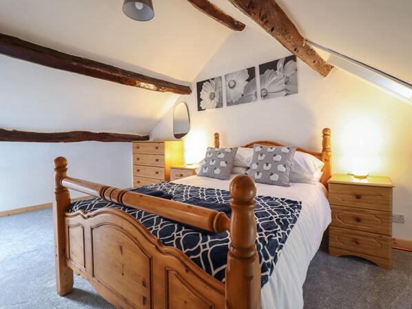 A bedroom with a wooden bed, a nightstand, a dresser, and a ceiling light.