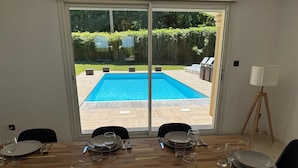 A dining area with a view of a swimming pool through large glass doors. - Villa located in St Augustin, near Royan, 5km from the Grande Côte beach. (Saint-Augustin)