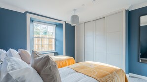 A bedroom with two beds, a window, and a wardrobe.