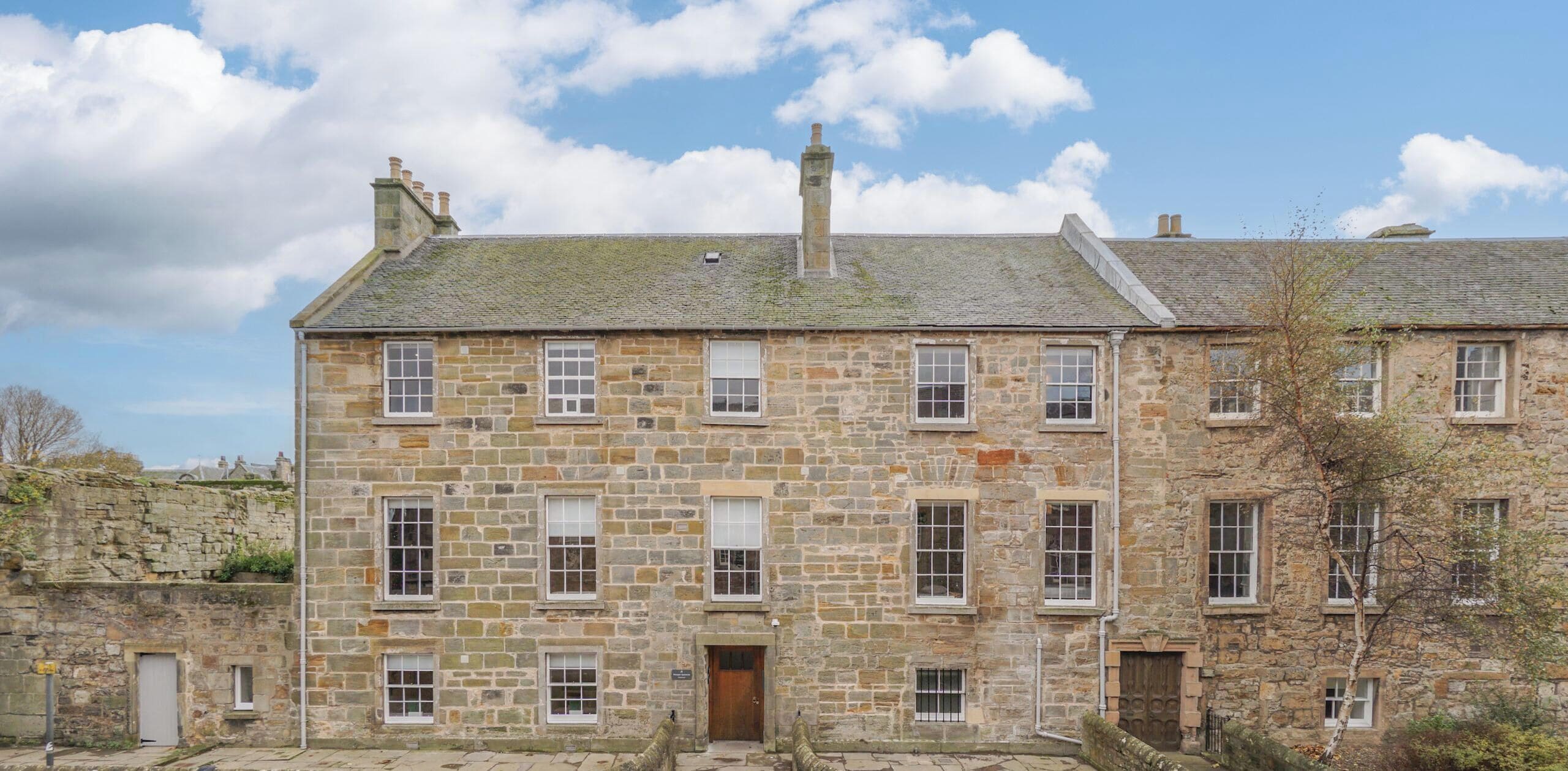 A stone building with multiple windows and a door, labeled "Short Stay St Andrews."