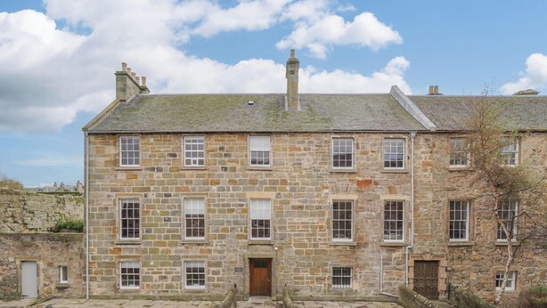 A stone building with multiple windows and a door, labeled "Short Stay St Andrews."