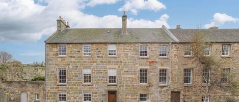 A stone building with multiple windows and a door, labeled "Short Stay St Andrews."
