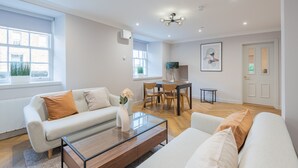 A modern living room with a sofa, coffee table, and dining area.