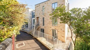 A modern building with a stone facade, a wooden deck, and a staircase leading to the entrance. - Lade Braes Apartments (No 22D) (St Andrews)