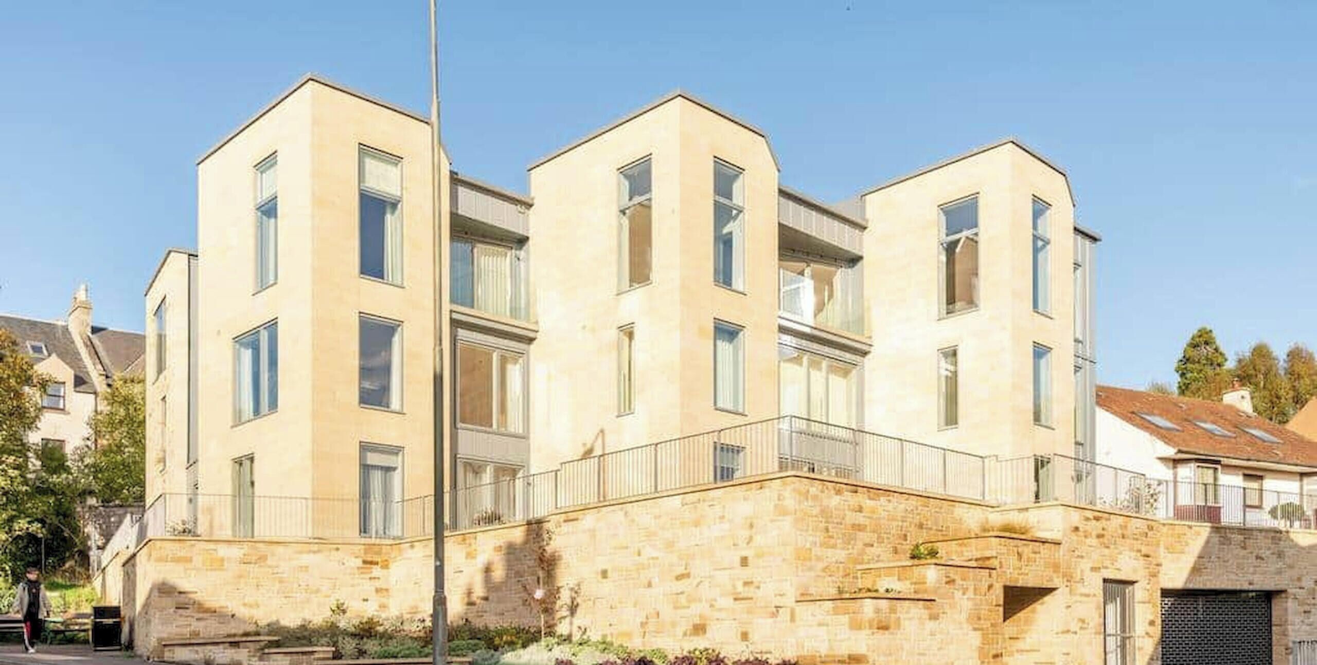 A modern multi-story building with a stone base, large windows, and a flat roof.