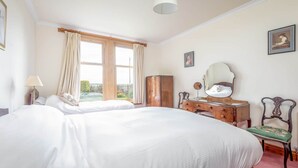 Un dormitorio con una cama grande, un aparador con espejo y una ventana con cortinas.