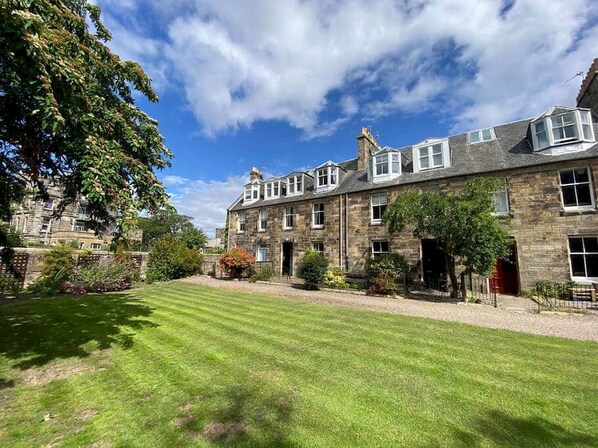 A stone building with a well-maintained lawn and a clear sky.