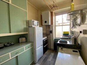 A compact kitchen with a refrigerator, microwave, and a sink area.
