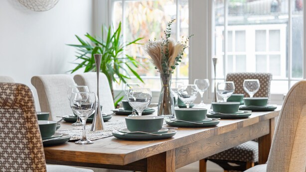 A dining table set with green plates, bowls, and wine glasses, surrounded by patterned chairs. - *| Perfectly Splendid Triplex House in Chelsea |*
 (London)